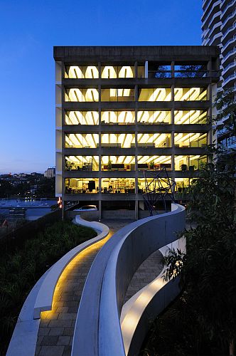 Curved ribbon wall and seating viewed against office building at dusk